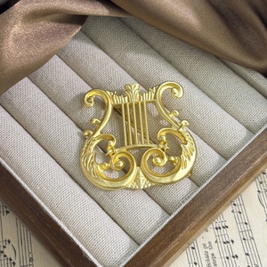 Macro detail of vintage matte gold harp brooch on elegant music sheet background