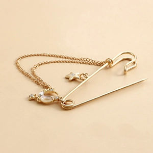 Close-up of golden star and moon charms with rhinestones on a double-chain brooch pin