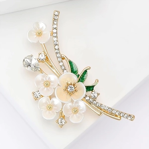 Elegant gold flower brooch with white enamel petals and sparkling zircon stones