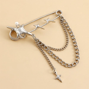 Detail of silver safety pin brooch with pentagram stars, pearls and layered cuban chains