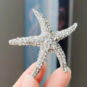 Broche étoile de mer vintage ornée de strass brillants tenue à la main pour détails