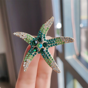 Gros plan sur une broche étoile de mer vintage avec strass verts sur alliage doré