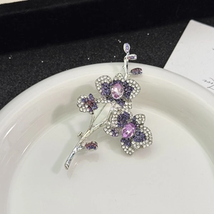 Détail de la broche orchidée violette élégante avec pavé de zircons sur une assiette