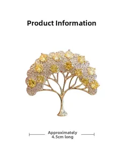 Dettaglio di una spilla ad albero dorata con cristalli gialli e misura di 4,5 cm