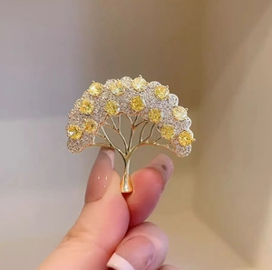 Dettaglio della spilla ad albero dei desideri dorata con zirconi e pietre preziose gialle
