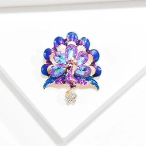 Detailed close-up of peacock brooch with blue enamel feathers and purple crystals