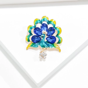 Macro shot of colorful peacock brooch with blue crystals and gold enamel finish