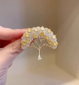 Dettaglio spilla ad albero dorata con cristalli gialli e pietre incastonate lucenti