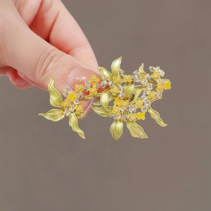 Detail of elegant enamel osmanthus brooch with yellow flowers and inlaid crystals