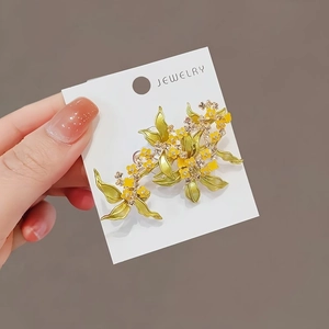 Elegant yellow osmanthus flower brooch with green leaves and zircon on a display card