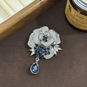 Elegant silver camellia flower brooch with blue gemstones and pear-shaped drop pendant