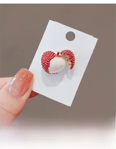Makro-Detail einer lycheeförmigen Brosche mit realistischer roter Textur und Fruchtfleisch