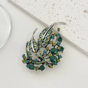 Detailed macro view of an elegant hollow leaf brooch with gradient green rhinestones