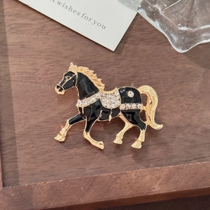 Macro view of horse-shaped brooch featuring black enamel inlay and white crystals