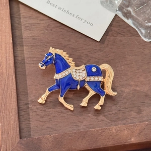 Detail of running horse brooch with blue enamel and sparkling crystals on golden alloy