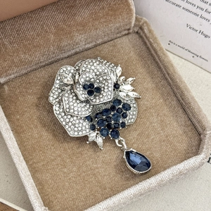 Detailed view of silver rose brooch with navy blue rhinestones and teardrop pendant
