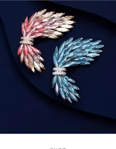 Dettaglio delle lussuose spille a forma di ala con cristalli in rosa e blu reale