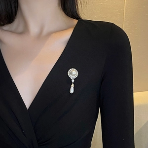 Elegant vintage style pearl brooch with zircon accents on a black v-neck dress