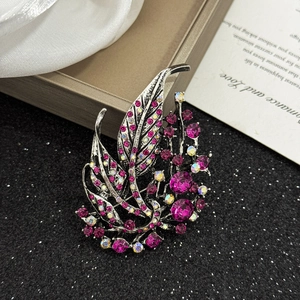 Elegant vintage hollow leaf brooch with ruby pink rhinestones on a dark textured background
