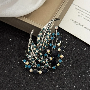 Elegant hollow leaf brooch with deep blue rhinestones on a vintage silver setting