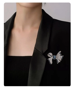 Détail d'une broche noeud argentée avec pierres bleues sur un revers de veste