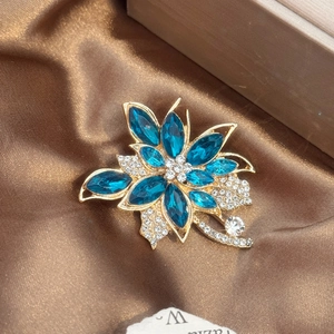 Gros plan sur une broche fleur en cristal bleu avec strass sur tissu en soie