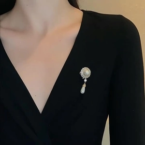Elegant vintage pearl brooch with teardrop pendant on black V-neck garment