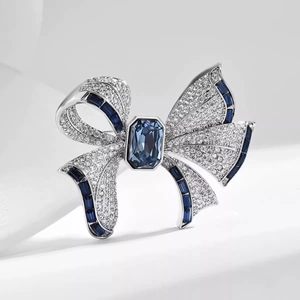 Gros plan d'une broche nœud ornée de cristaux bleus et de diamants blancs sur métal argenté