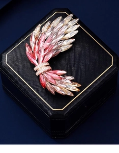 Dettaglio di una spilla ad ala di lusso con cristalli rosa sfumati e finitura oro