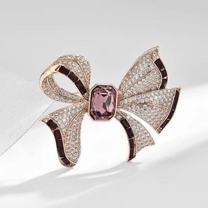 Vue macro d'une broche nœud en or rose avec pierre violette et strass blancs brillants