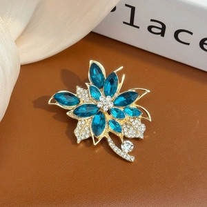 Broche fleur élégante avec cristaux bleu foncé et strass blancs sur base dorée