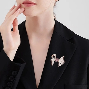 Élégante broche nœud en or rose avec pierre violette et perles sur le revers d'un tailleur