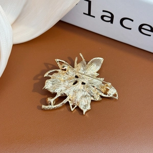 Détail de l'envers d'une broche fleur dorée montrant la texture des feuilles et le fermoir