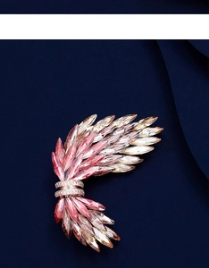 Dettaglio della spilla a forma di ala con cristalli sfumati rosa su tessuto di seta blu