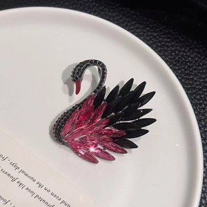 Exquisite crystal swan brooch with gradient black and pink stones on a ceramic plate