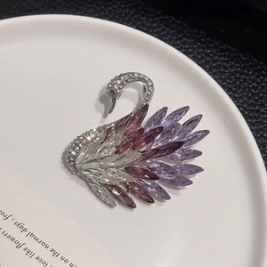 Detailed close-up of a crystal swan brooch with pink marquise-cut stones and silver plating
