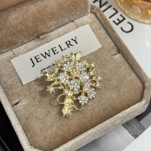 Détail macro d'une broche bouquet de fleurs luxueuse en métal doré et strass blancs