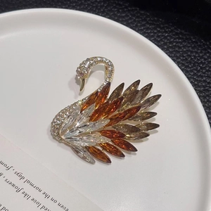 Detailed close-up of crystal swan brooch with gradient amber and grey rhinestones