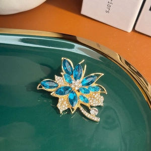 Broche florale exquise avec cristaux marquise bleus et zircons sur monture dorée