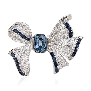 Broche nœud élégante avec pierres bleues et cristaux blancs sur fond blanc