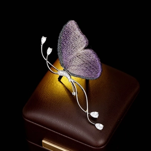 Détail macro des ailes en maille violette et zircons étincelants sur broche papillon