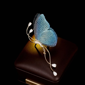 Détail macro de broche papillon brodée bleue avec monture dorée et pierres scintillantes