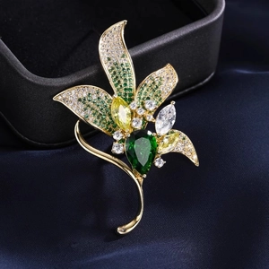 Détail d'une broche magnolia en cristal avec pierre verte et métal doré poli