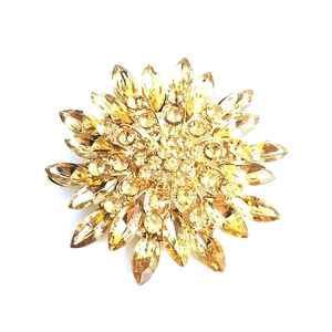 Detailed close-up of magnolia brooch with golden plating and amber crystal petals