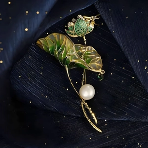 Detailed macro shot of vintage lotus brooch with green enamel leaves and white pearl drop