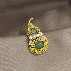 Hollow gold gourd brooch with green gemstones and pearls on brown silk fabric
