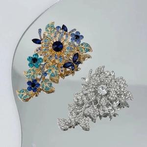 Macro shot of luxury vintage flower brooches with blue crystals and a mirrored reflection