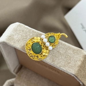 Detail of vintage Chinese hollow gold brooch with green jade and pearls on jewelry box
