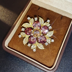 Elegant floral brooch with purple crystal petals and champagne center in a velvet box