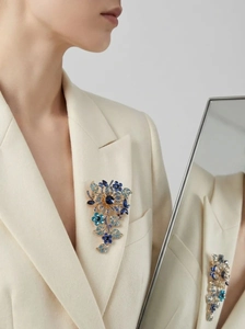 Luxurious flower brooch with blue crystals shown on a beige blazer with a mirror reflection